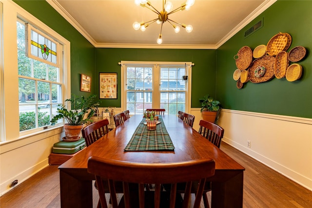 dining area featuring crown molding, an inviting chandelier, dark wood-type flooring, and plenty of natural light