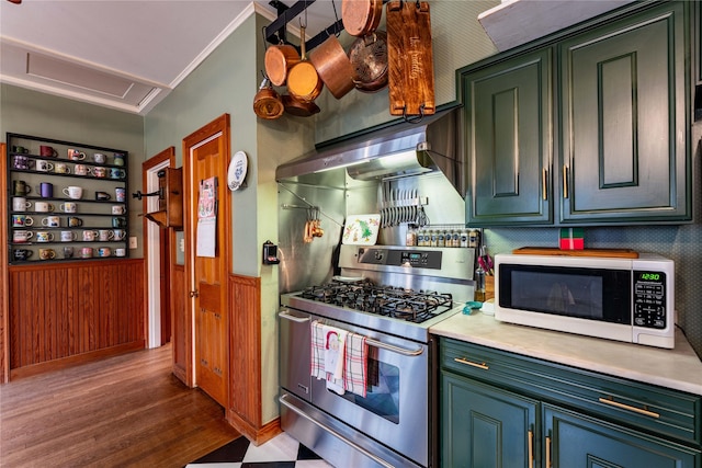 kitchen featuring hardwood / wood-style floors, wooden walls, wall chimney range hood, crown molding, and stainless steel range with gas stovetop