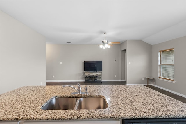 kitchen featuring light stone counters, dishwashing machine, baseboards, and a sink