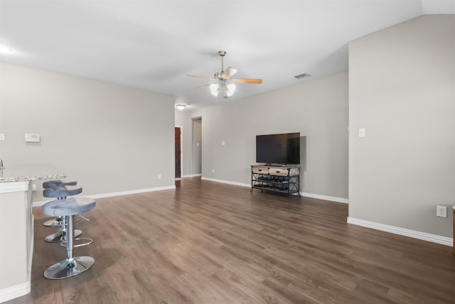 unfurnished living room featuring dark hardwood / wood-style floors, ceiling fan, and vaulted ceiling