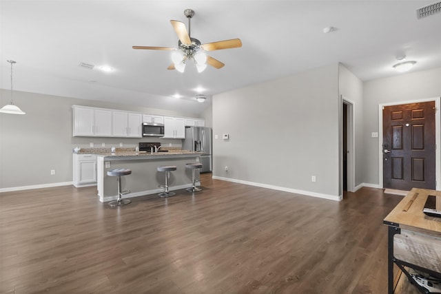 kitchen featuring a kitchen bar, a center island with sink, dark hardwood / wood-style flooring, white cabinetry, and stainless steel appliances