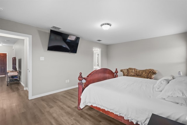 bedroom featuring visible vents, baseboards, and wood finished floors