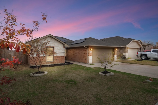 view of front facade with driveway, solar panels, a front lawn, a garage, and brick siding