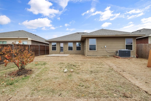back of house featuring central AC, a patio, a fenced backyard, roof with shingles, and a lawn