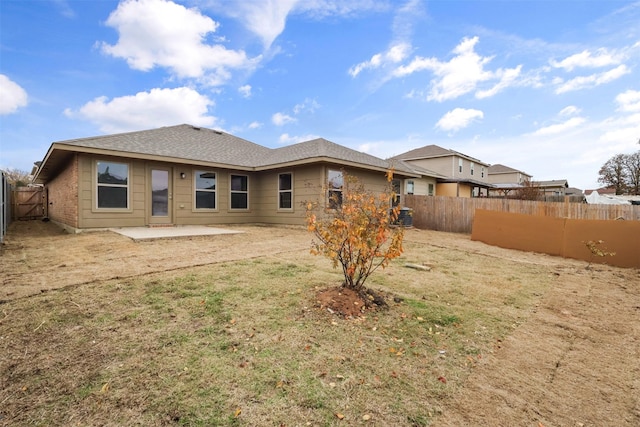 rear view of property with a fenced backyard, a lawn, and a patio