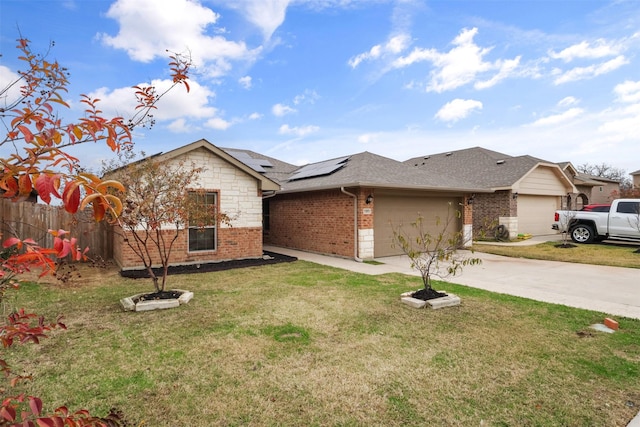 view of front of house featuring driveway, a front yard, a garage, brick siding, and roof mounted solar panels