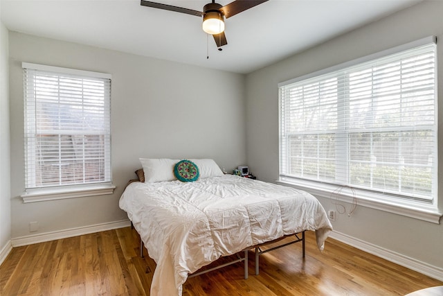 bedroom featuring ceiling fan, light hardwood / wood-style floors, and multiple windows