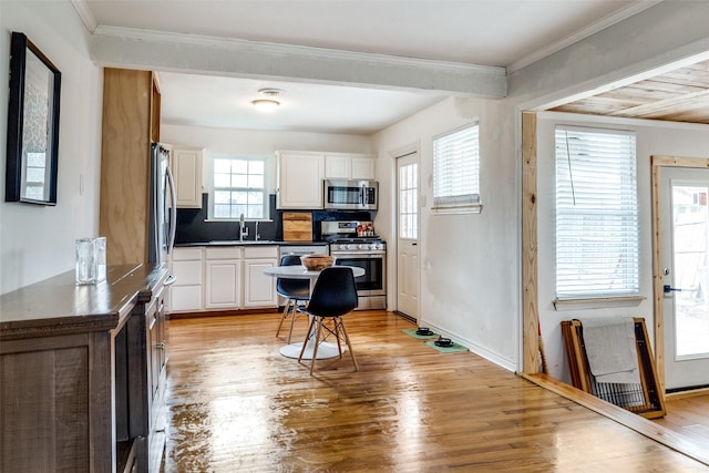 kitchen featuring white cabinets, stainless steel appliances, light hardwood / wood-style flooring, and tasteful backsplash