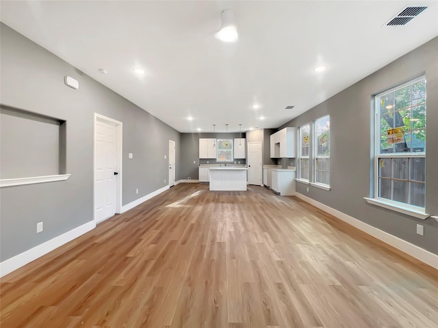 unfurnished living room with sink and light wood-type flooring