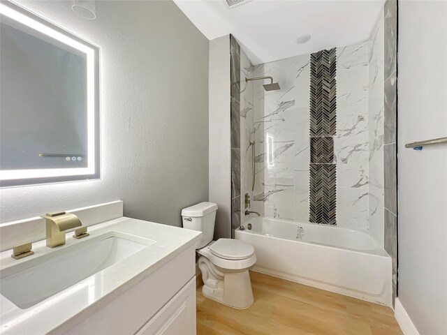 full bathroom with hardwood / wood-style flooring, tiled shower / bath combo, toilet, and vanity