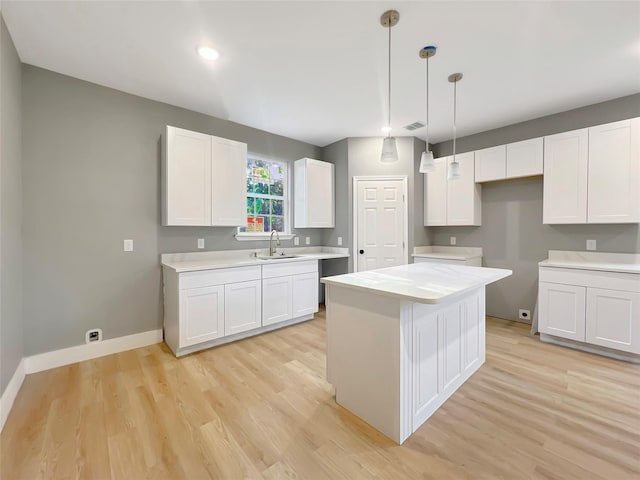 kitchen with white cabinetry, sink, and light hardwood / wood-style flooring