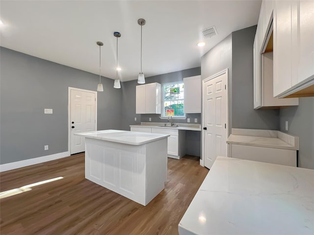 kitchen featuring white cabinetry, sink, dark wood-type flooring, pendant lighting, and a kitchen island