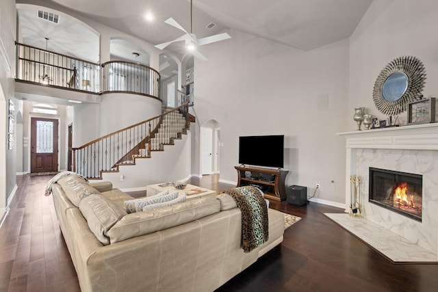 living room with a premium fireplace, high vaulted ceiling, dark hardwood / wood-style floors, and ceiling fan