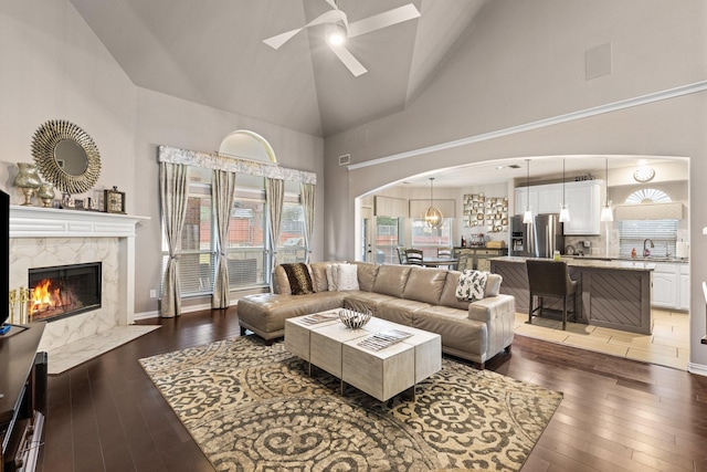 living room with ceiling fan, a premium fireplace, dark hardwood / wood-style flooring, and high vaulted ceiling