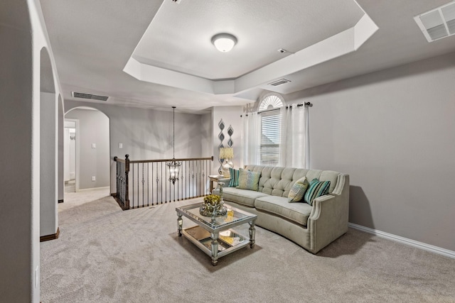 living room featuring a tray ceiling and carpet floors