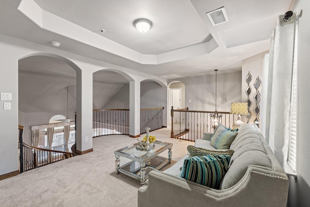 carpeted living room with a tray ceiling