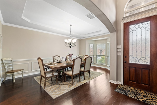 dining area featuring crown molding, dark wood-type flooring, and a raised ceiling