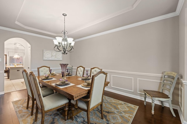 dining area with dark hardwood / wood-style flooring, a notable chandelier, and a raised ceiling