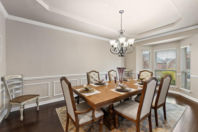 dining space featuring a notable chandelier, dark hardwood / wood-style floors, ornamental molding, and a raised ceiling