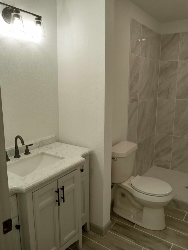 bathroom featuring vanity, toilet, and a tile shower