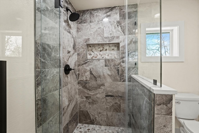 bathroom with toilet and a tile shower