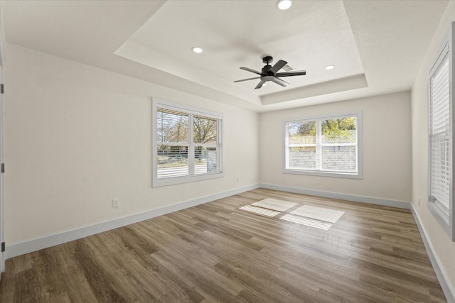 spare room featuring hardwood / wood-style flooring, a raised ceiling, and ceiling fan