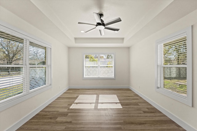 spare room featuring ceiling fan, hardwood / wood-style flooring, and a raised ceiling