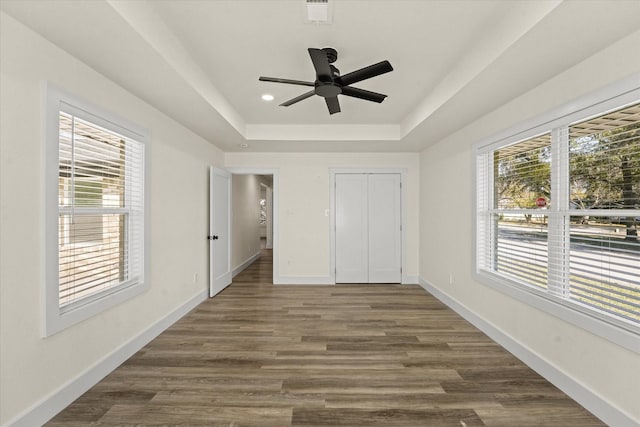 unfurnished bedroom with ceiling fan, multiple windows, a closet, and a raised ceiling