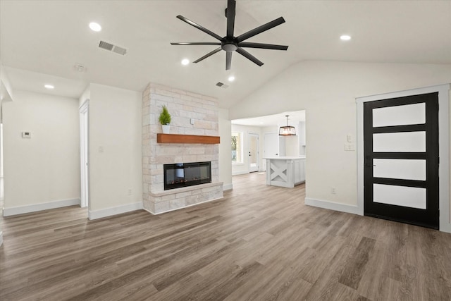 unfurnished living room featuring ceiling fan, lofted ceiling, a fireplace, and hardwood / wood-style floors