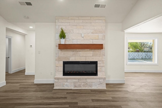 unfurnished living room with dark hardwood / wood-style floors, lofted ceiling, and a stone fireplace