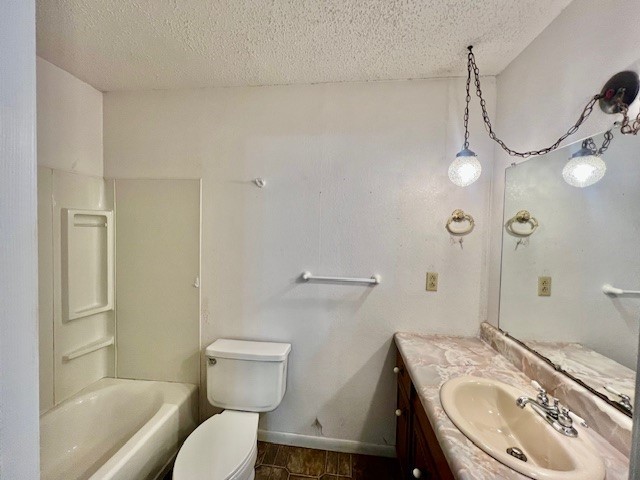 full bathroom featuring vanity, a textured ceiling, toilet, and tub / shower combination