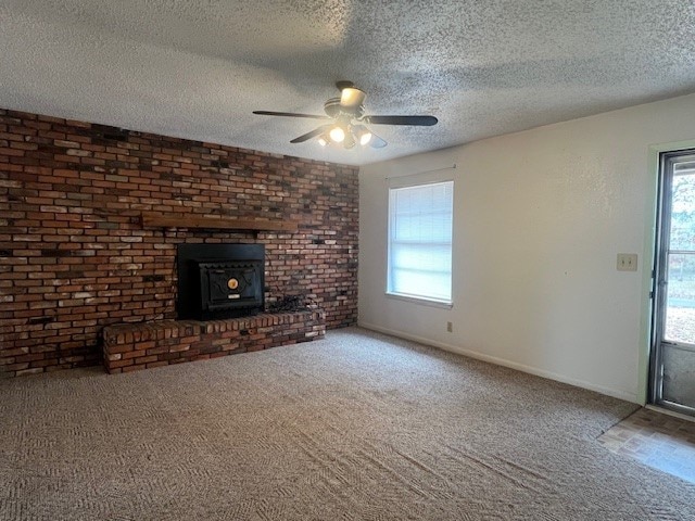 unfurnished living room featuring ceiling fan, a wood stove, a textured ceiling, and carpet floors