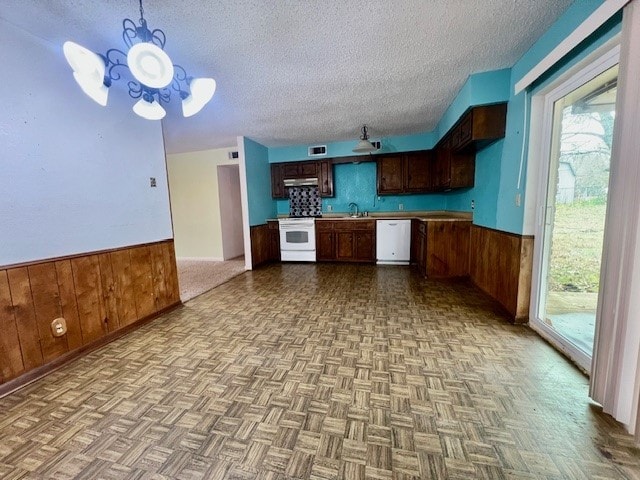 kitchen with sink, wood walls, light parquet floors, a textured ceiling, and white appliances