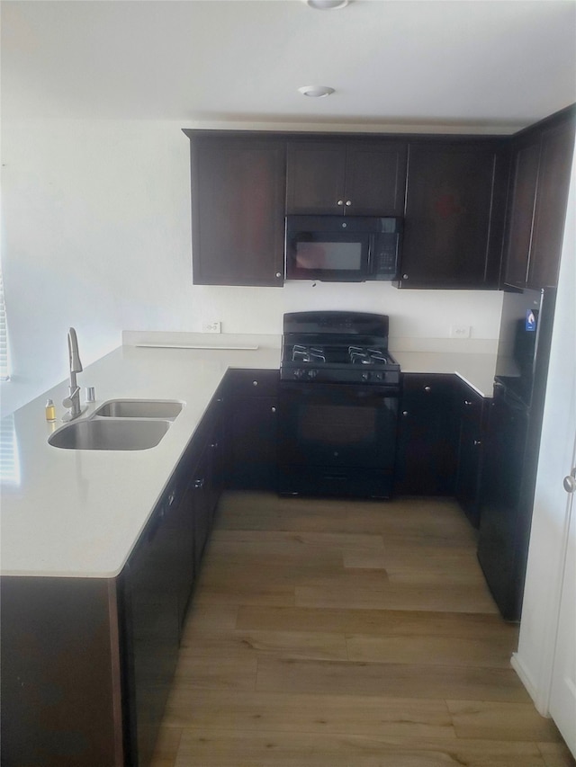 kitchen featuring sink, black appliances, dark brown cabinets, and light hardwood / wood-style floors