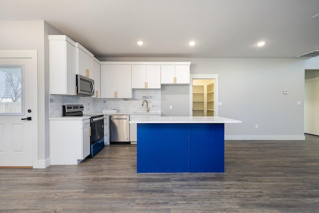 kitchen featuring dark wood-type flooring, stainless steel appliances, a kitchen island, tasteful backsplash, and white cabinets