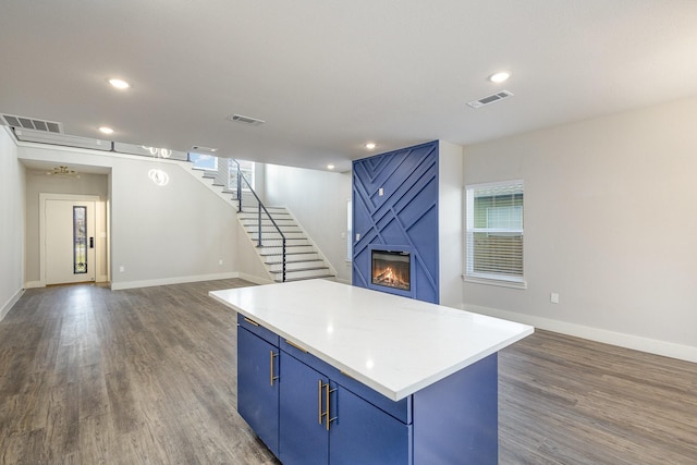 kitchen with a fireplace, a kitchen island, dark wood-type flooring, and blue cabinets