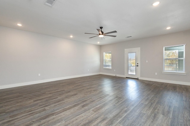 unfurnished room with dark wood-type flooring, ceiling fan, and a healthy amount of sunlight