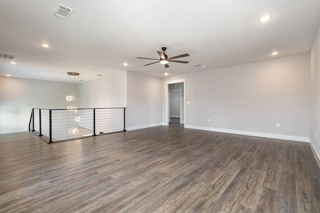 spare room with ceiling fan with notable chandelier and dark hardwood / wood-style floors