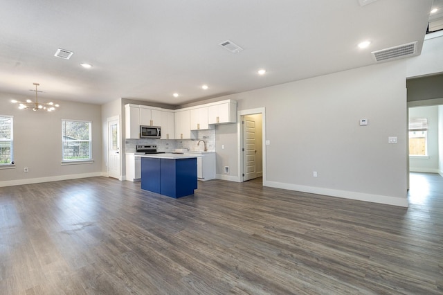 kitchen featuring pendant lighting, dark wood-type flooring, white cabinets, appliances with stainless steel finishes, and a kitchen island