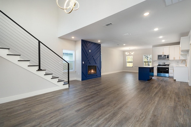 unfurnished living room with dark hardwood / wood-style floors, sink, a fireplace, and an inviting chandelier