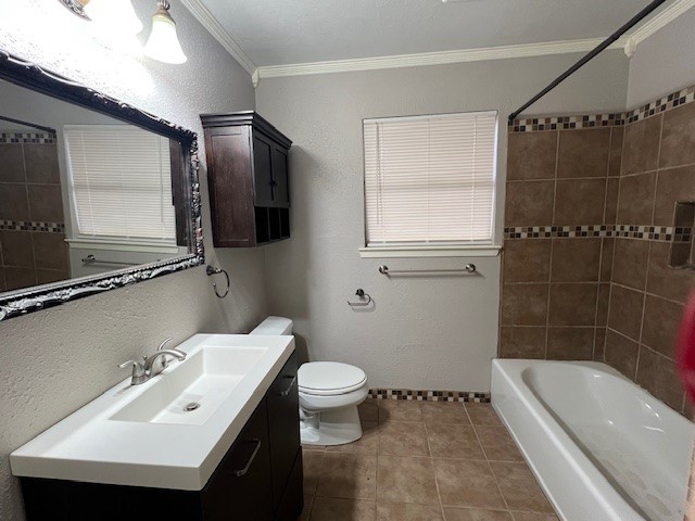 full bathroom featuring tiled shower / bath, tile patterned flooring, vanity, toilet, and crown molding