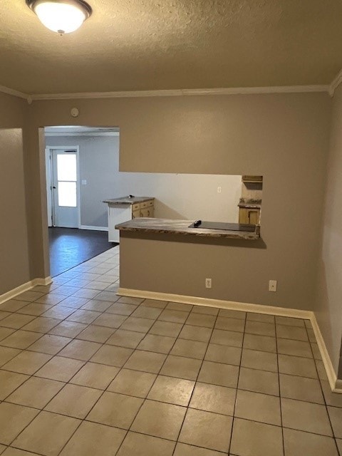 interior space featuring light tile patterned floors, a textured ceiling, and ornamental molding