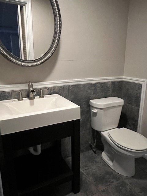 bathroom with tile patterned flooring, vanity, toilet, and tile walls