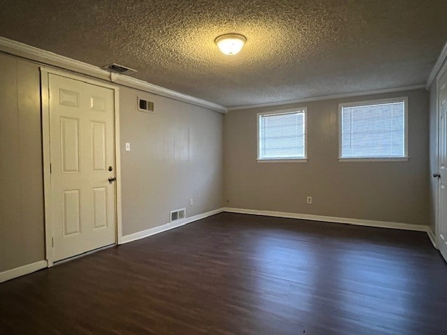 spare room featuring crown molding, dark hardwood / wood-style floors, and a textured ceiling