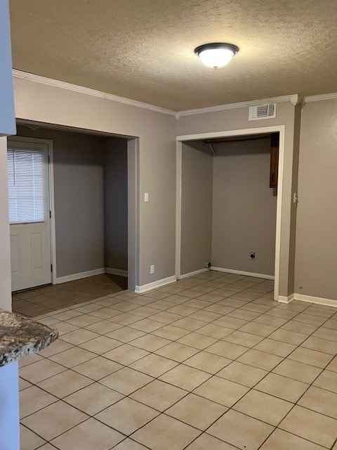 basement featuring light tile patterned floors, a textured ceiling, and ornamental molding