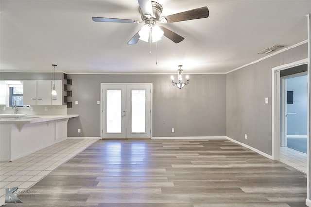 unfurnished living room featuring a healthy amount of sunlight, ceiling fan with notable chandelier, and ornamental molding