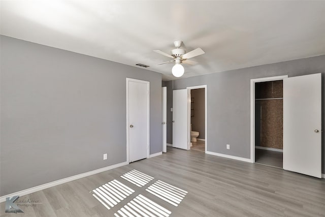 unfurnished bedroom featuring ceiling fan, connected bathroom, light hardwood / wood-style floors, a spacious closet, and a closet