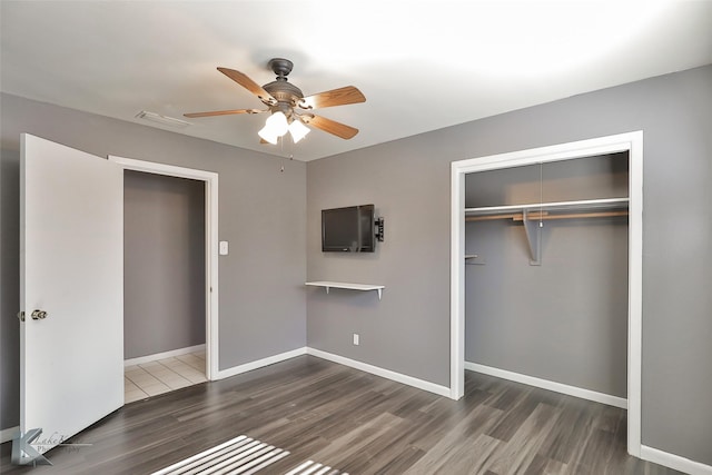 unfurnished bedroom featuring dark hardwood / wood-style flooring, ceiling fan, and a closet