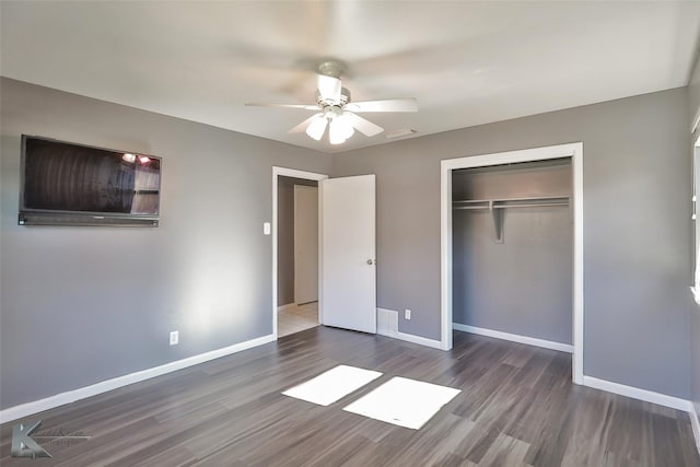 unfurnished bedroom with dark hardwood / wood-style flooring, ceiling fan, and a closet