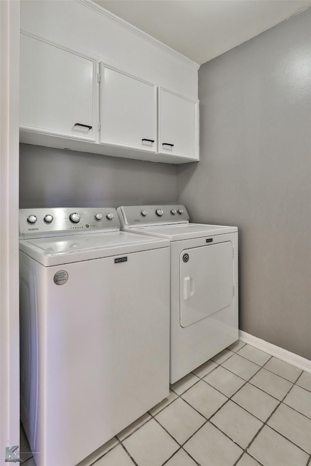 washroom with washing machine and dryer, light tile patterned flooring, and cabinets